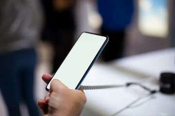  a caucasian man holds new smartphone with white screen copyspace. close up, soft focus. background in blur © Maria