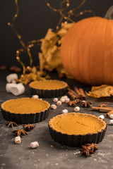 Yellow pumpkin pie orange  pumpkins with yelllow dry autumn leaves decor on dark table background.Harvesting,autumn and Thanksgiving concept