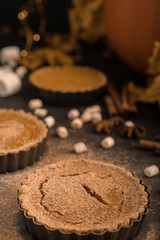 Yellow pumpkin pie orange  pumpkins with yelllow dry autumn leaves decor on dark table background.Harvesting,autumn and Thanksgiving concept