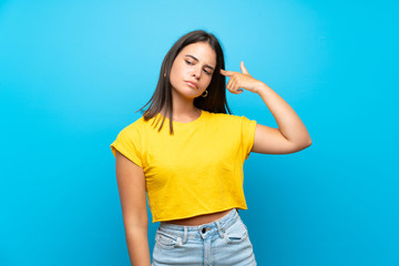 Young girl over isolated blue background making the gesture of madness putting finger on the head