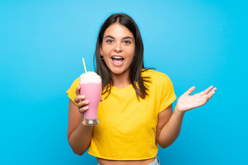 Young girl with strawberry milkshake over isolated background with shocked facial expression