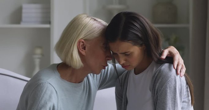 Worried mature mother comforting sad young daughter apologizing reconciling