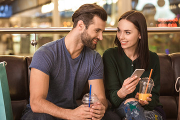Young adult husband and wife resting in shopping mall