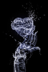 Fototapeta na wymiar The hand made of water is keeping heart made of water on the black background. Happy Valentine's Day