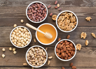 Different kinds of nuts in ceramic bowls. With honey.