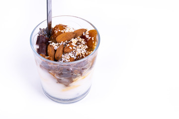 A vegan desert made of chia pudding, yoghurt, jam, fruit, cookies and almonds on white background