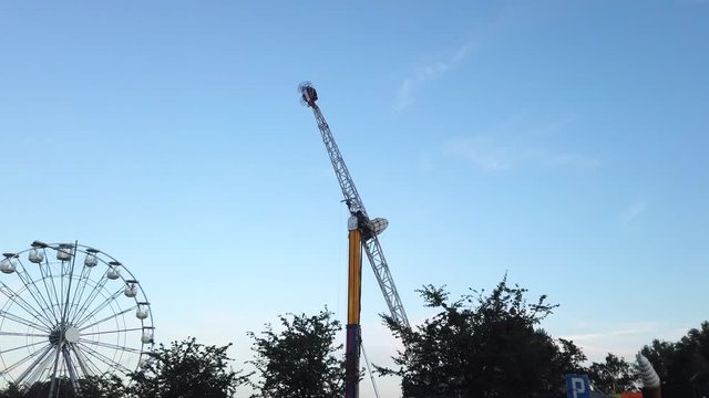 Gdynia, Kosciuszki square. Roller Coaster and ferris wheel in an amusement park. Hammer rollercoaster spinning around.