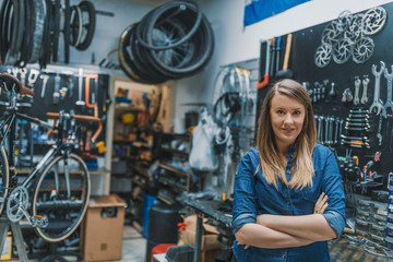 Obraz na płótnie Canvas Portrait of young female mechanic in bicycle store