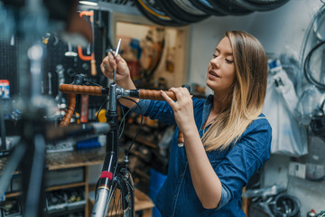 Woman bicycle mechanic is repairing a bike in the workshop