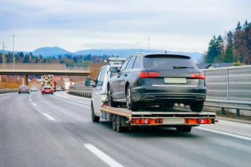 Tow truck with car on warranty in road. Trailer and crash auto delivery. Vehicles hauler on...