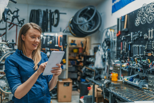 Female mechanic at work. Verify the checklist. Mechanic woman checking something on a tablet-pc and checklist. - Powered by Adobe
