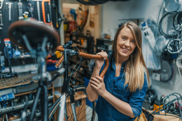 Obraz na płótnie Canvas Woman bicycle mechanic is repairing a bike in the workshop