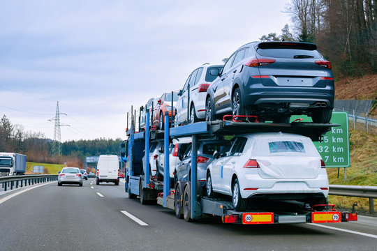 Car carrier transporter truck on road. Auto vehicles hauler on driveway. European transport logistics at haulage work transportation. Heavy haul trailer with driver on highway.