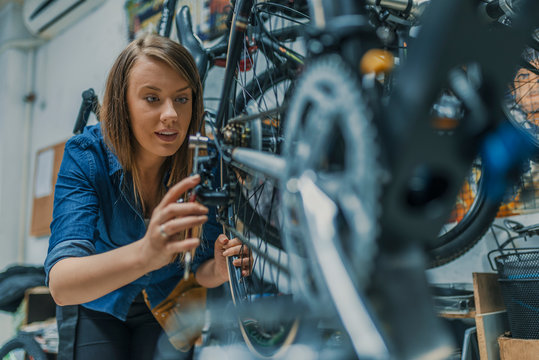 Young woman working in a biking repair shop - Powered by Adobe