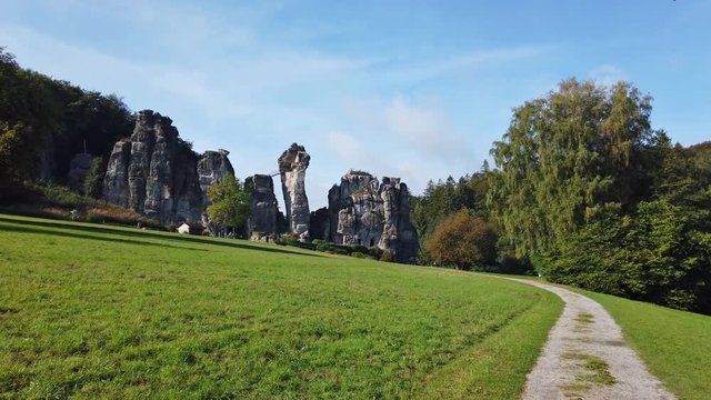 The historic sandstone rocks of Externsteine in East Westphalia in Germany. It is autumn. The sky is blue and the sun is shining. Camera pan.