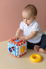 Cute little baby girl concentrated on opening-closing doors on her toy