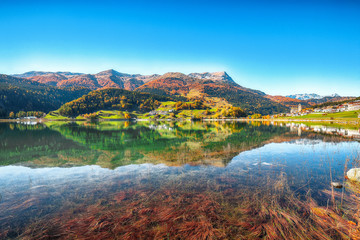 Bright autumn view of San Valentino village and Muta lake (Haidersee)