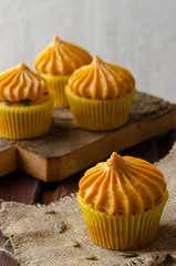 Pumpkin cupcakes with pumpkin-caramel cream wooden Background