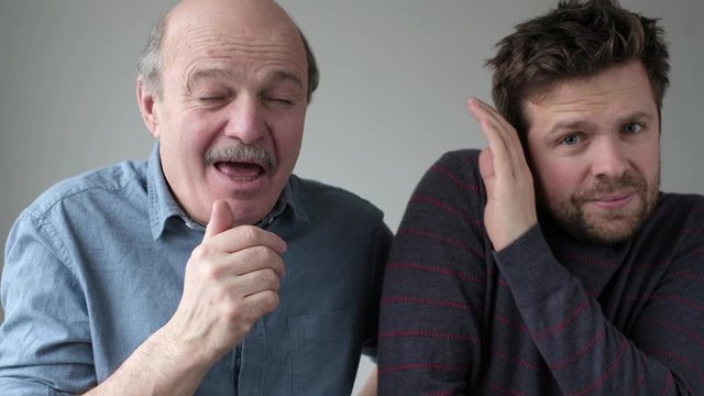 Man holding sneezing with closed eyes. His coworker try to hide from microbes.