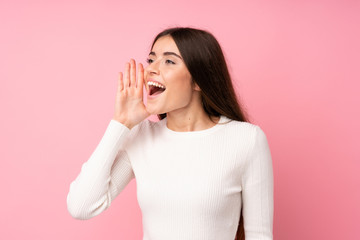 Young woman over isolated pink background shouting with mouth wide open