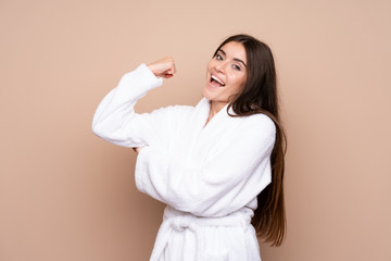 Young girl in a bathrobe over isolated background making strong gesture