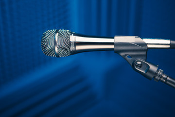 Fototapeta premium microphone on stand, blue background with acoustic foam wall in studio