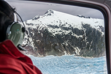 Passenger of the helicopter is looking on the glacier from the window. Amazing snowy mountain...