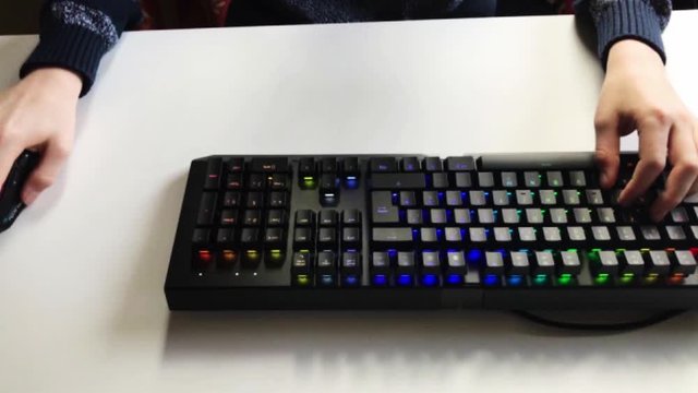 Kind spielt am PC mit einer farbigen Tastatur