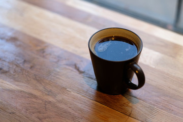 one cup of black coffee on wooden empty table in cafe