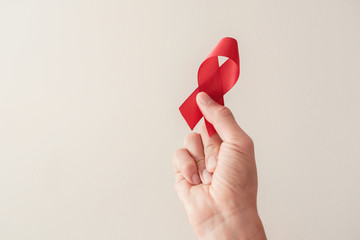 Hand holding red ribbon, hiv awareness concept, world AIDS day, world hypertension day - obrazy, fototapety, plakaty