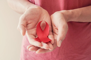 Hands holding red ribbon, hiv awareness concept, world AIDS day, world hypertension day