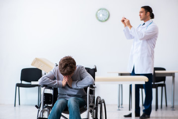 Young male doctor pediatrist and boy in wheel-chair