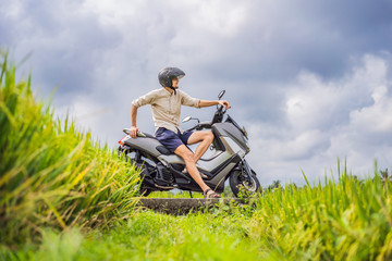 Naklejka na ściany i meble Male traveler on a bike among a rice field. Tourist travels to Bali