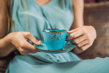 Young woman having a mediterranean breakfast seated at sofa and drinks hot aromatic coffee