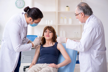 Obraz premium Two male doctors and young woman in plastic surgery concept