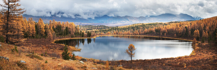 Picturesque lake in the mountains of Altai. Autumn day. Forested shores,  reflection in water.