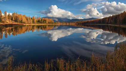 Obraz premium Picturesque lake in the mountains of Altai. Autumn day. Beautiful sky reflection with clouds in the water.