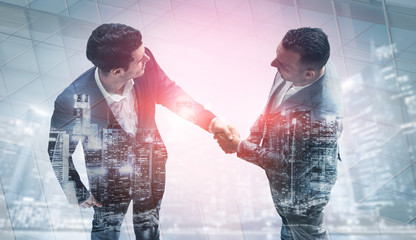Double exposure image of business people handshake on city office building in background showing...