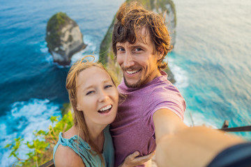 Fototapeta na wymiar Family vacation lifestyle. Happy couple - man and woman stand at viewpoint. Look at beautiful beach under high cliff. Travel destination in Bali. Popular place to visit on Nusa Penida island