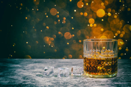 Whiskey and ice on a golden bokeh background for Happy Day.