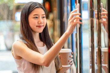 Asian young woman hand using smart mobile phone scanning the movie tickets machine for buy and get the coupon in department store,lifestyle and leisure,entertain and technology scanner concept