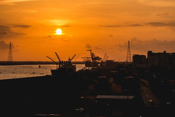 Fototapeta premium Silhouette of heavy crane tool in ship port and contain stock at sunset scene
