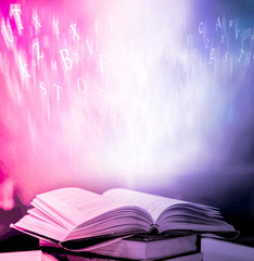  Imagine opening an old book blurred with magic power on the table and the English alphabet floating above the book with magic light as a beautiful background design.