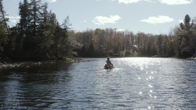 Aerial view of young female paddling in a canoe on a lake in the fall 07
