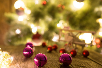 Obraz na płótnie Canvas Christmas holiday background with wooden airplane and christmas red balls on wooden table top over festive bokeh light decorate on Christmas tree.