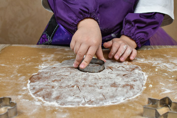 Children's hands cut out cookie dough with cookie cutters. Christmas, winter, new year. Fir-trees, stars, flour. Close-up.