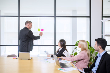 Diverse business people using sticky notes on glass wall