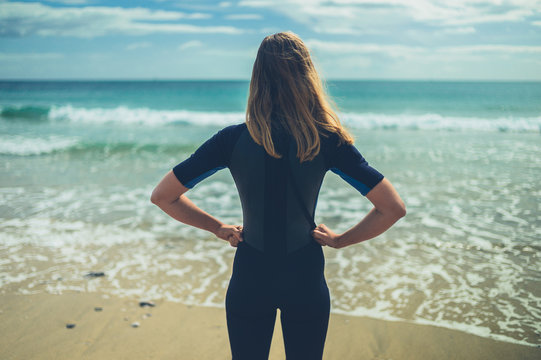 Young woman in wetsuit standing on the beach