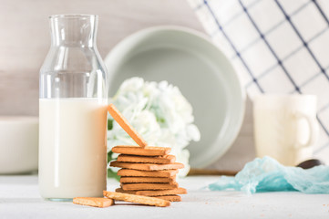Fresh cookies and milk in bottle on light background