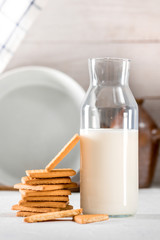 Fresh cookies and milk in bottle on light background